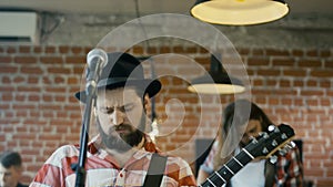 Emotional bearded guitarist singing into microphone