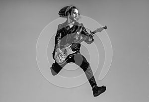 emotional bearded rock musician playing electric guitar in leather jacket and jumping, guitar player