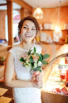 Emotional beautiful bride with wedding bouquet in interior, joyful surprised face, facial expression.