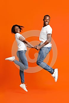 Emotional black couple in love holding hands and jumping up