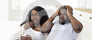 Emotional black couple watching horror movie on tv