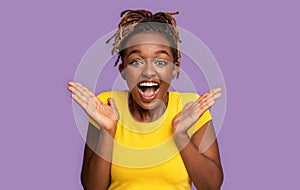 Emotional black girl expressing amazement over purple background