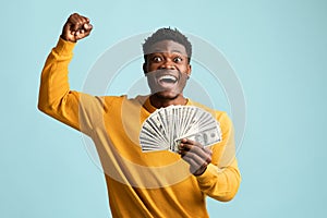 Emotional black guy with cash celebrating success