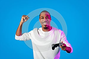 Emotional black guy playing video game on blue background