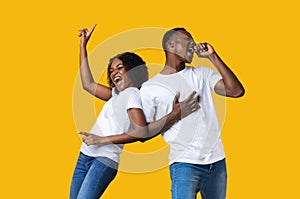 Emotional black man and woman dancing and singing on yellow