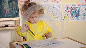 Emotional blonde girl child draw with pencil in book on table