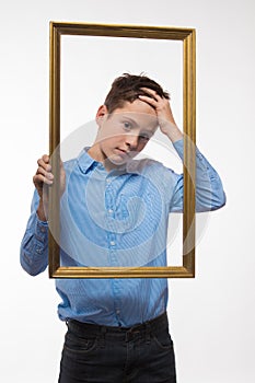 Emotional boy brunette in a blue shirt with a picture frame in the hands