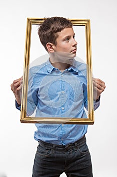 Emotional boy brunette in a blue shirt with a picture frame in the hands