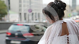 emotional bride in urban landscape, smiling and whirling near road in downtown of big city