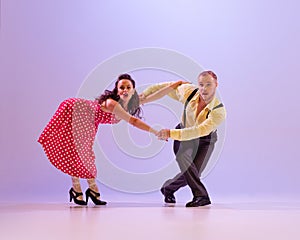 Emotional bright couple of dancers in colorful retro style attires dancing incendiary dances  on purple