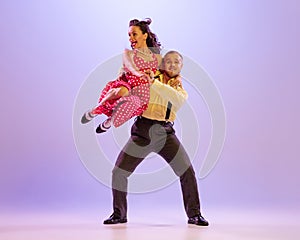 Emotional bright couple of dancers in colorful retro style attires dancing incendiary dances  on purple