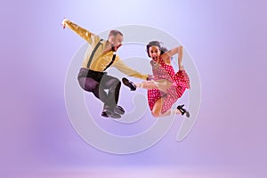 Emotional bright couple of dancers in colorful retro style attires dancing incendiary dances  on purple