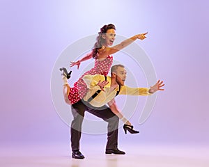 Emotional bright couple of dancers in colorful retro style attires dancing incendiary dances  on purple