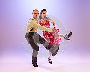 Emotional bright couple of dancers in colorful retro style attires dancing incendiary dances  on purple