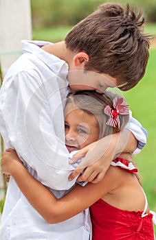 Emotional brother hugging sister in the park outdoors
