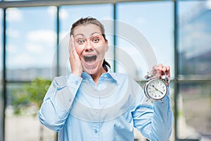 Emotional businesswoman with an alarm clock in shock