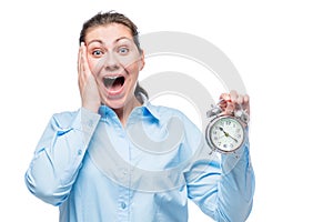Emotional businesswoman with an alarm clock in shock on a white