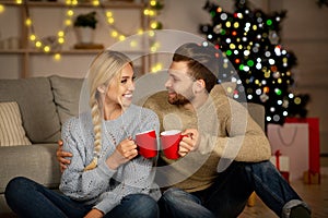Emotional Christmas couple embracing and drinking cocoa