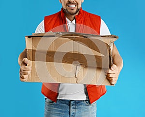 Emotional courier with damaged cardboard box on blue background. Poor quality delivery service