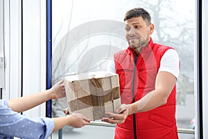 Emotional courier giving damaged cardboard box to client in doorway, closeup. Poor quality delivery service