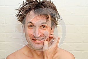 Emotional crazy caucasian man with bristles and shaggy hair, on white brick background think about troubles