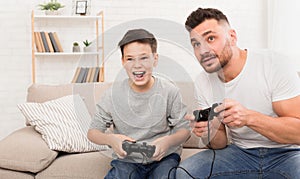 Emotional dad and son competing on gamepad at home