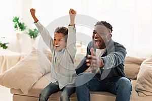 Emotional Dad And Son Watching Sport On TV At Home