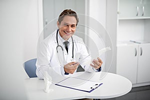Emotional doctor holding spine model and smiling