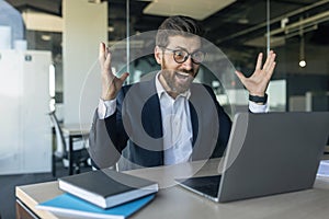 Emotional excited mature businessman using laptop, celebrating success, raising hands, reading news and screaming yes,