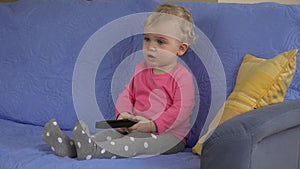 Emotional female child with remote control in hands concentrated on television