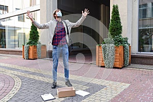 Emotional, frustrated young man, office worker in a medical mask on strike in the street. Crisis, business, lifestyle.