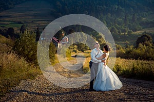 Emotional full-length shot of the cheerful newlywed couple laughing and having fun during the walk along the countryside