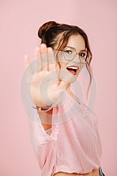 Emotional girl in glasses with two buns making stop gesture, blocking camera