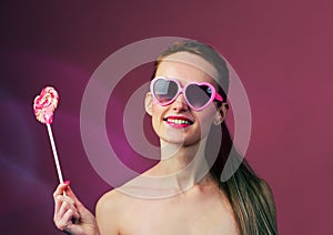 emotional girl with a lollipop over pink background