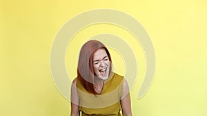 Emotional girl with red hair shouting over yellow background.