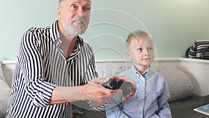 Emotional grandfather plays with his grandson in computer games with a joystick