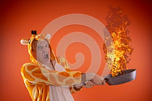Emotional guy holding a frying pan in his hands, on an orange background.