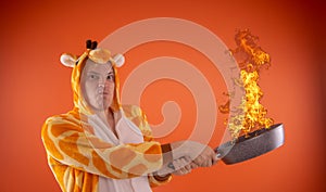 Emotional guy holding a frying pan in his hands, on an orange background.