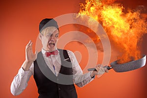 Emotional guy holding a frying pan in his hands, on an orange background.