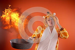 Emotional guy holding a frying pan in his hands, on an orange background.