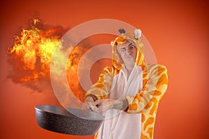 Emotional guy holding a frying pan in his hands, on an orange background.