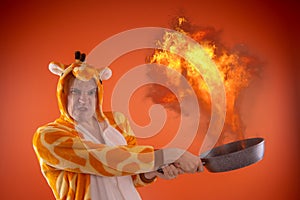 Emotional guy holding a frying pan in his hands, on an orange background.