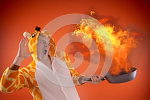 Emotional guy holding a frying pan in his hands, on an orange background.