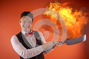 Emotional guy holding a frying pan in his hands, on an orange background.