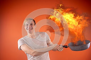 Emotional guy holding a frying pan in his hands, on an orange background.