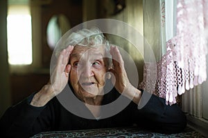 Emotional happy old lady tells gesturing at a table in the house