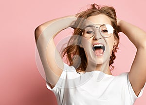 Emotional happy woman in glasses screaming shouting yelling closeup portrait on pink background