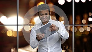 Emotional Indian businessman palying game on digital tablet.