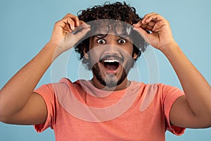 Emotional indian man removing eyeglasses and looking at camera