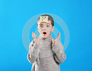 Emotional little boy with question mark on blue background